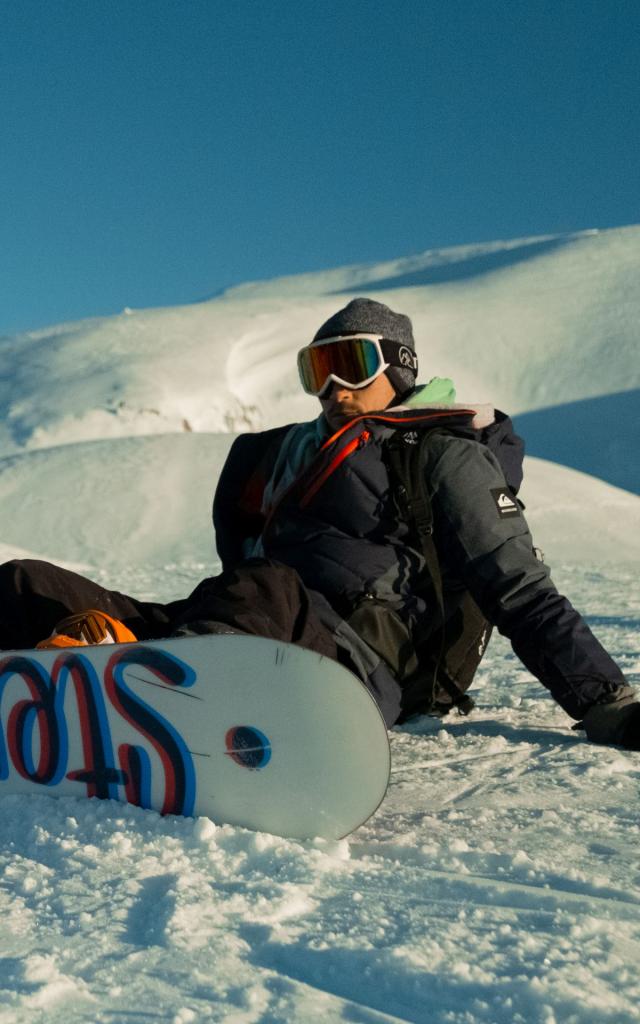 snowboarder à la station de la Pierre Saint-Martin qui fait une pause avec vue sur les sommets enneigés